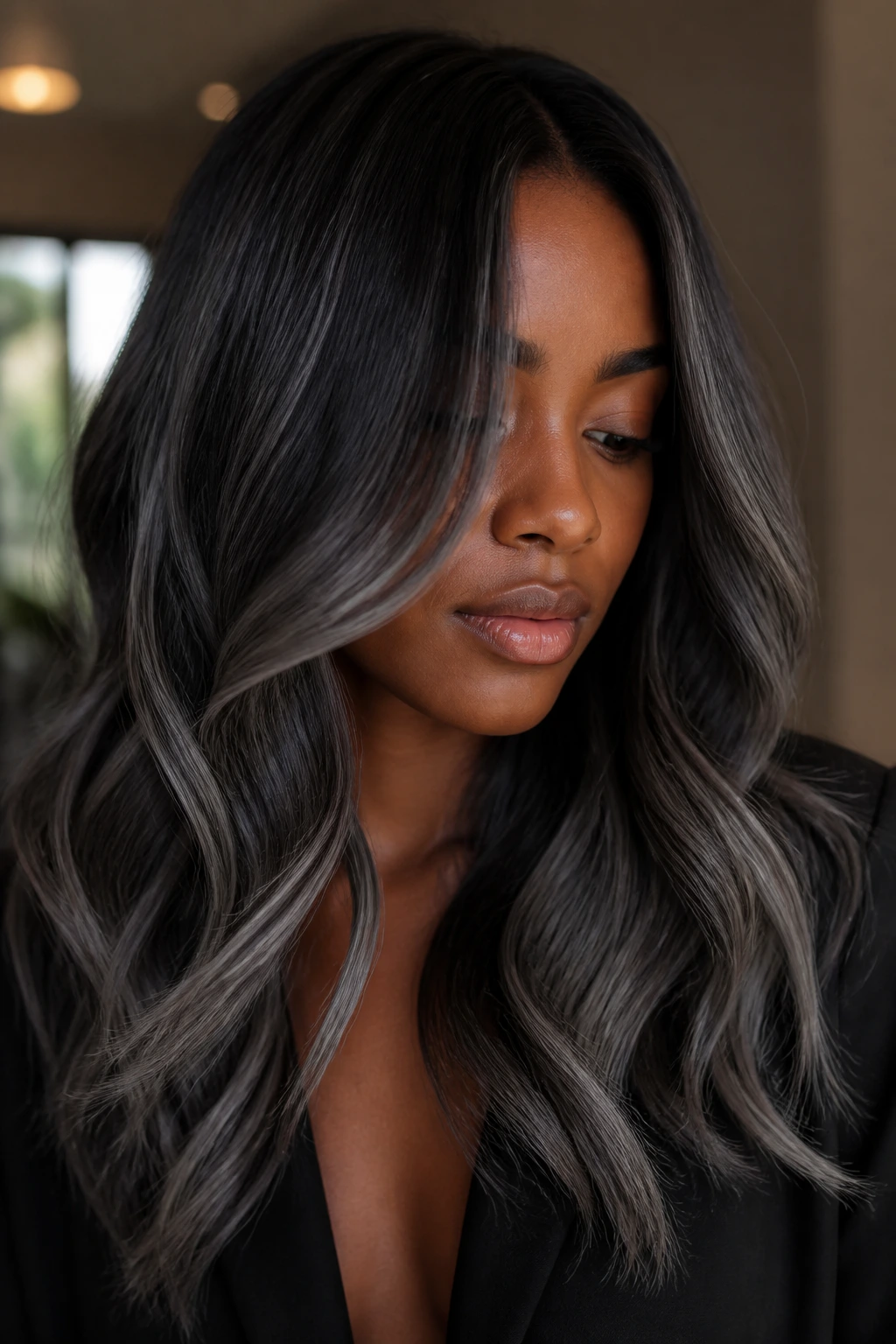 Close-up of a person with graphite balayage ribbons in hair against deep skin tone.