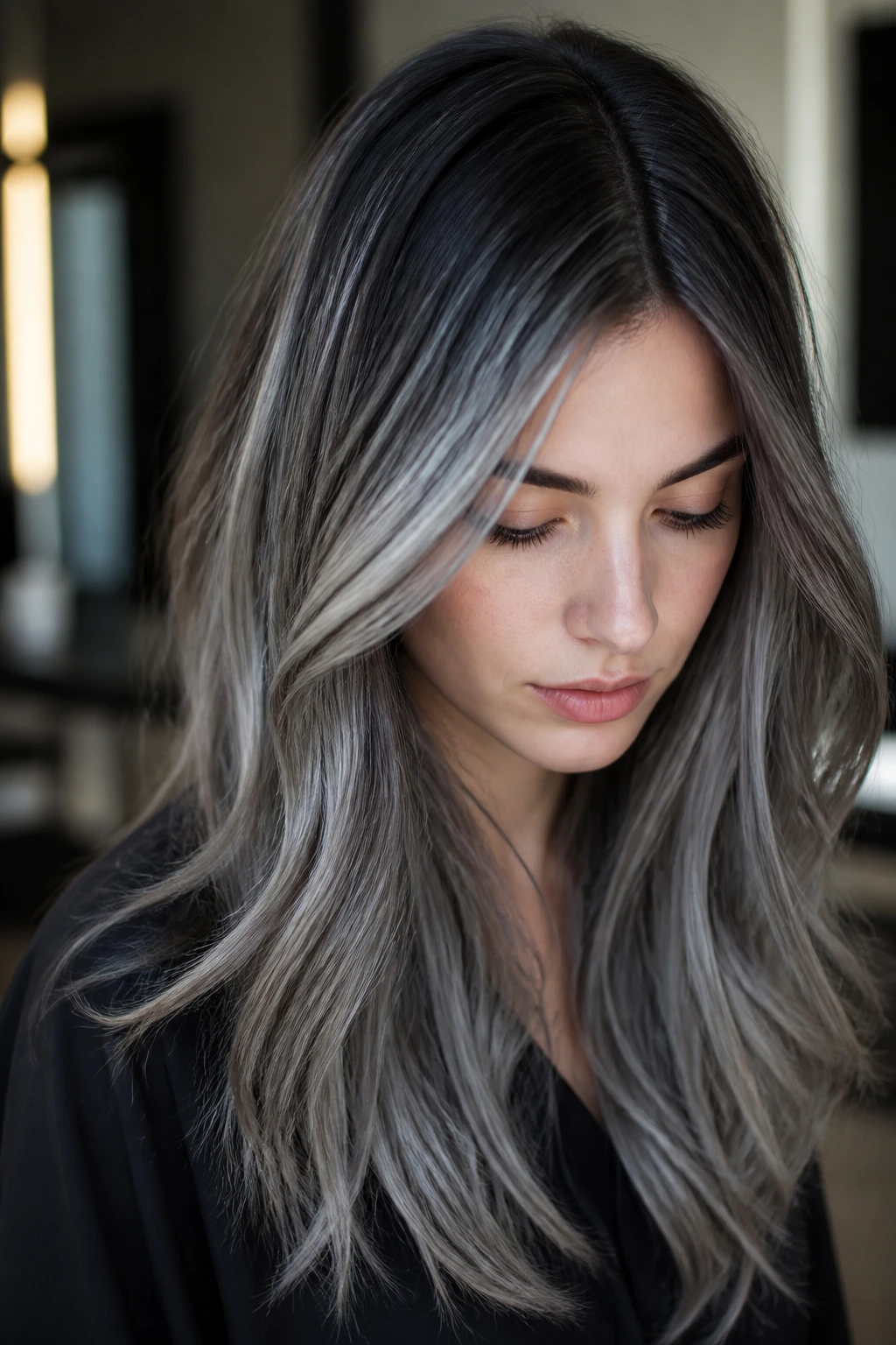 Close-up portrait showing graphite root melt from dark roots to smoky silver.