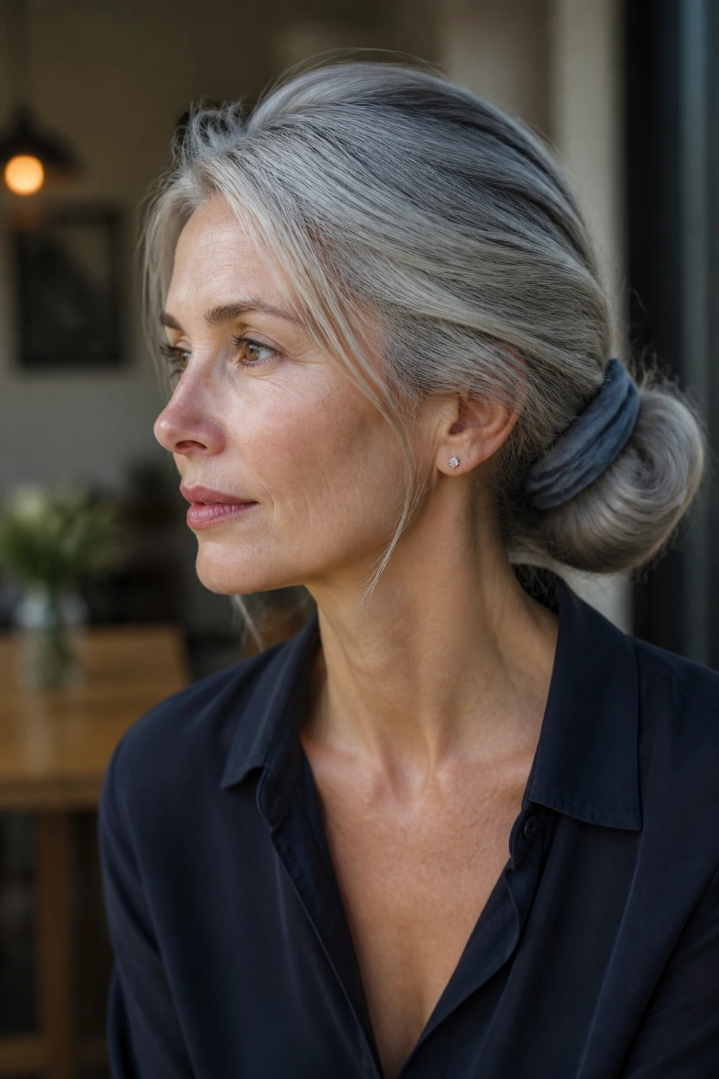 Close-up of a real person with long gray hair in a scarf-wrapped low chignon