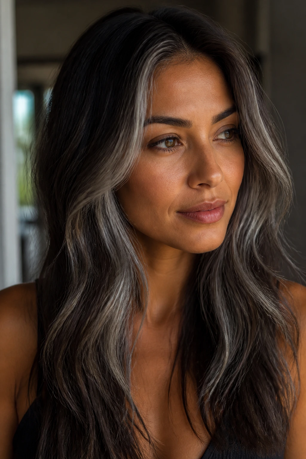 Portrait of a person with tan skin and hair showcasing graphite grey lowlights against dark brown base
