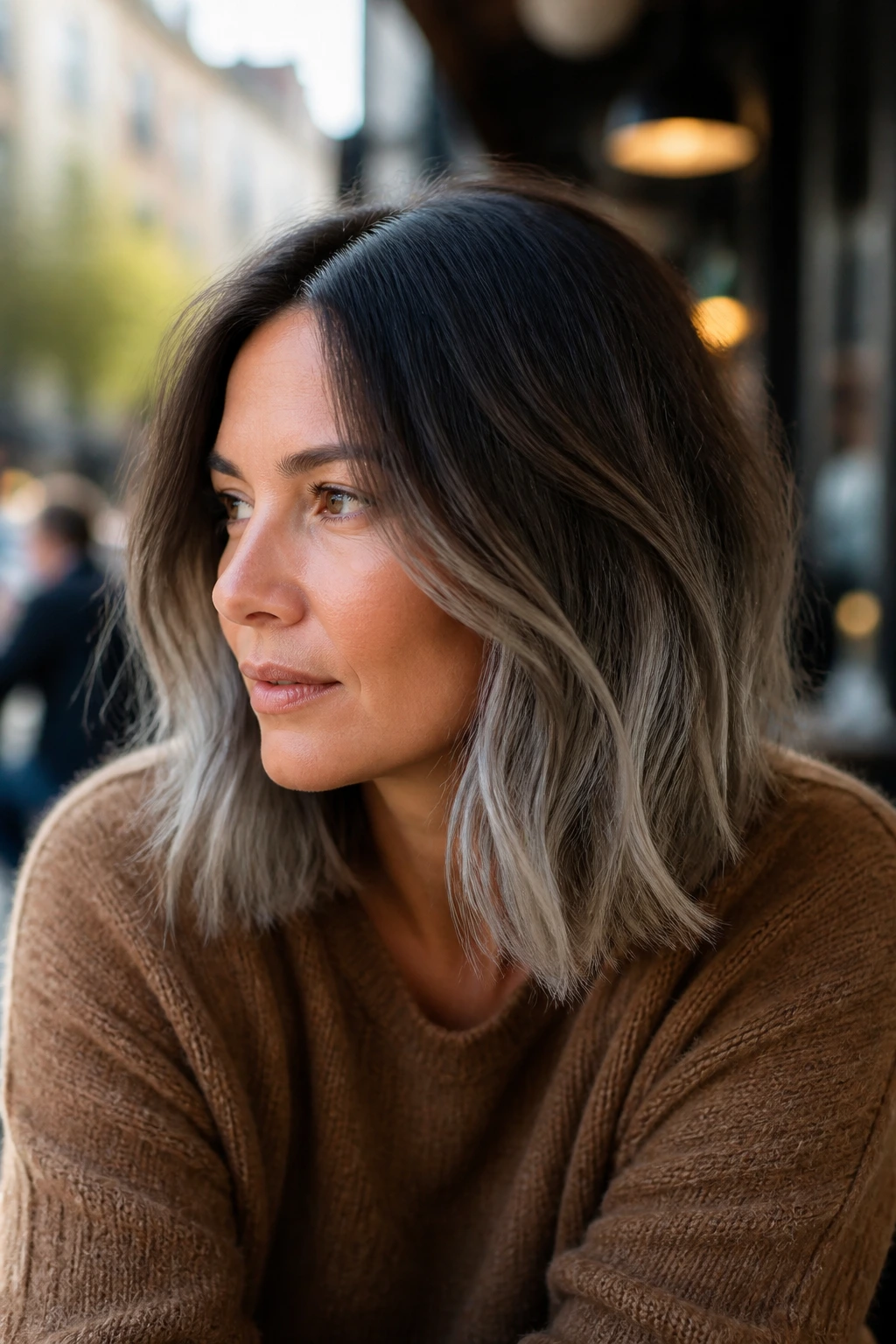 Real woman with grown-out lob and dark roots fading to grey ends.