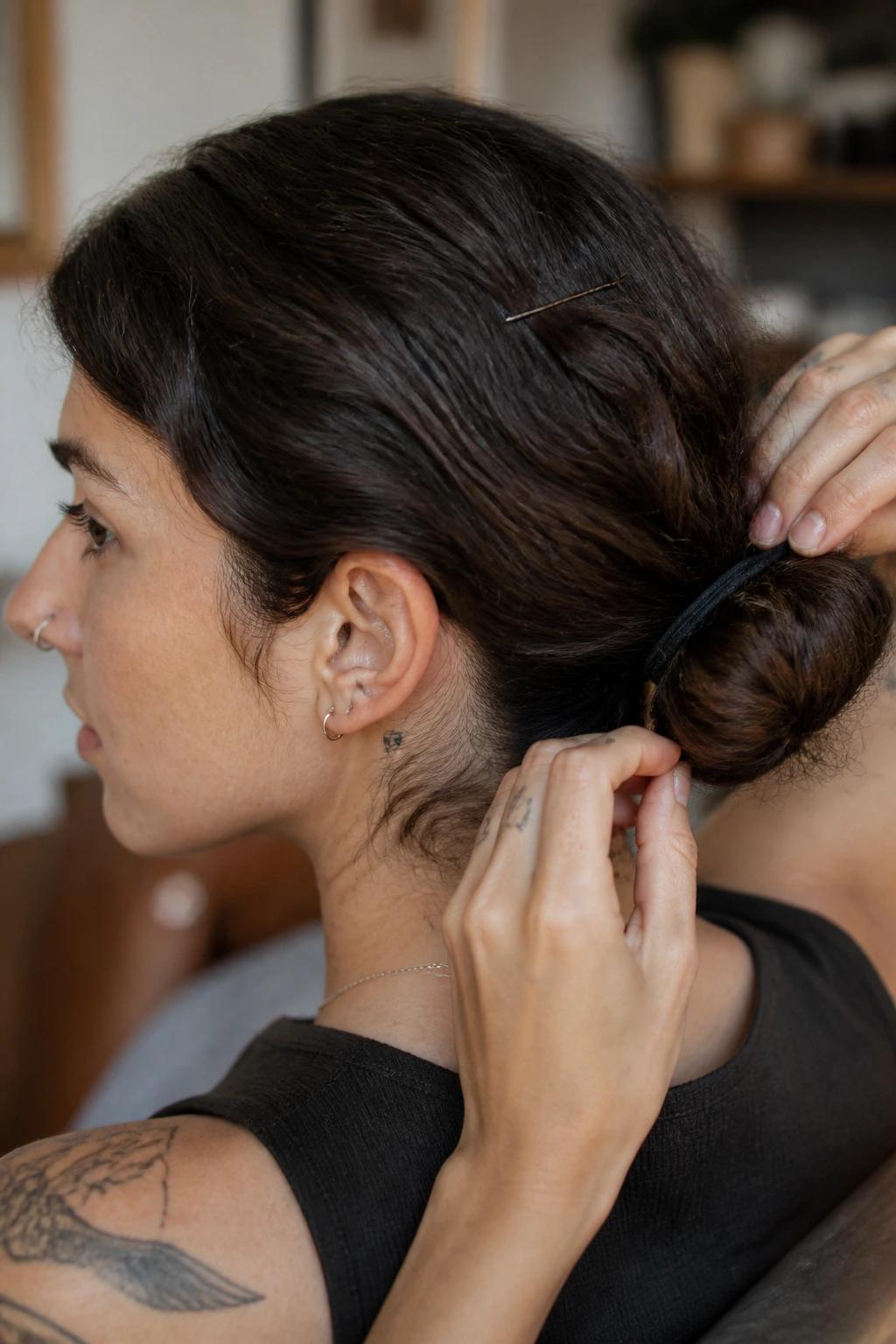 Portrait of a person adjusting a low bun with pins and elastic.