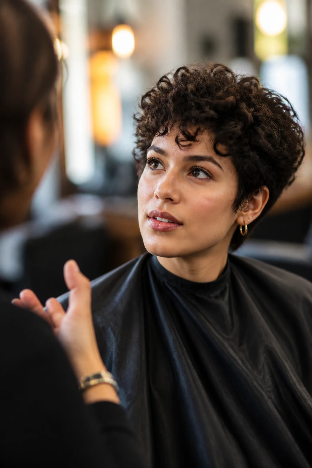 Salon consultation portrait showing a client discussing a curly pixie for oval face.