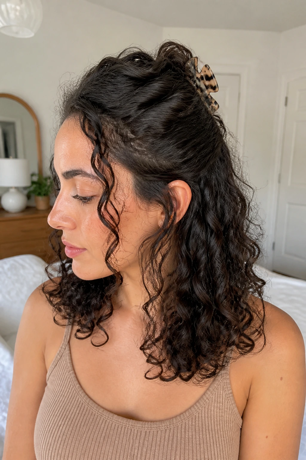 Close-up of a real woman with a half-up twist secured by a claw clip and loose curls