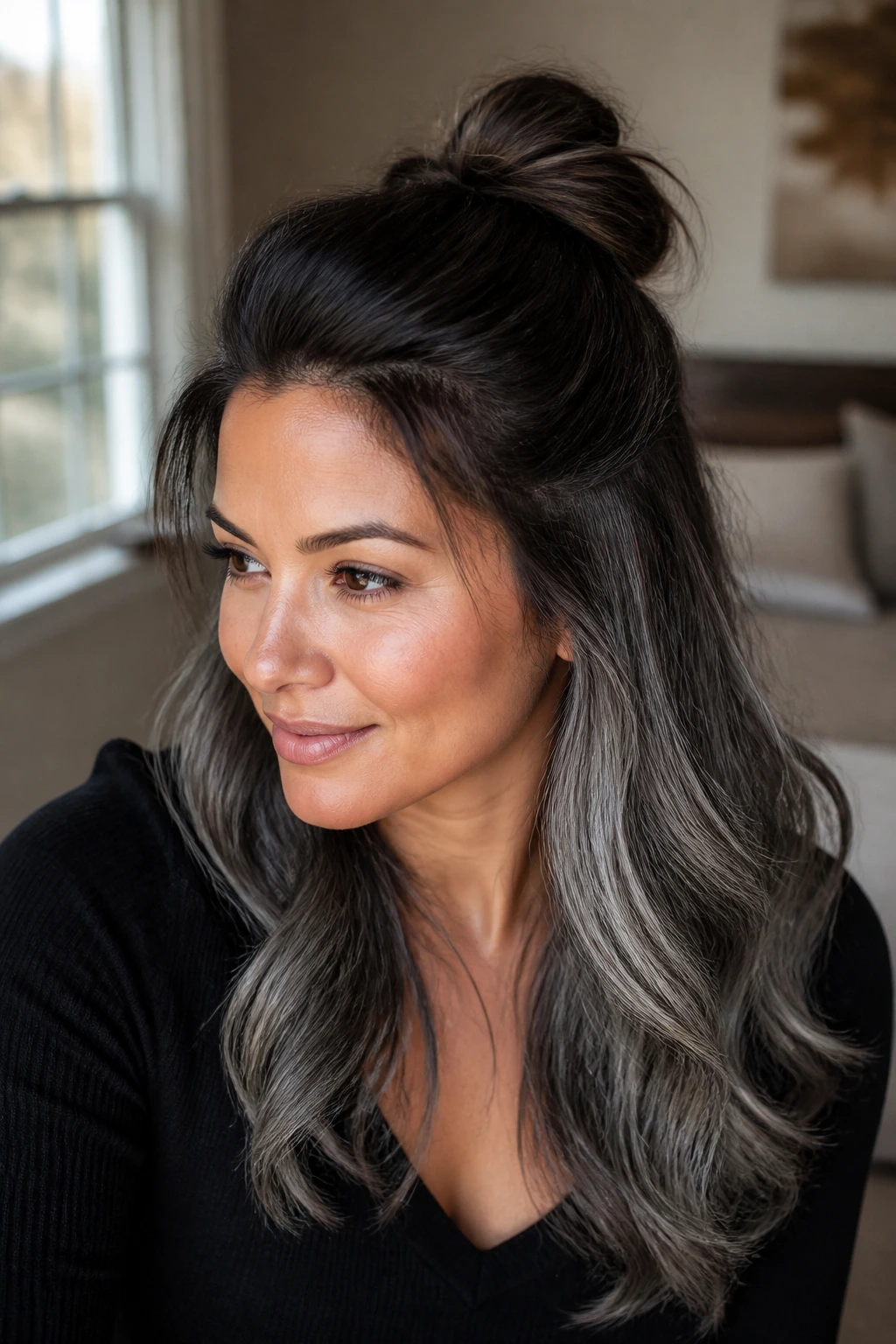 Close up of a real woman with a half-up knot showing brown to grey lengths on tan skin