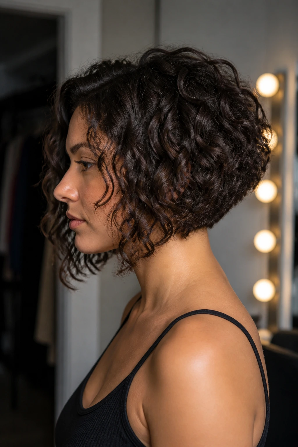 Side-profile of a real woman with inverted curly lob showing back shorter front longer