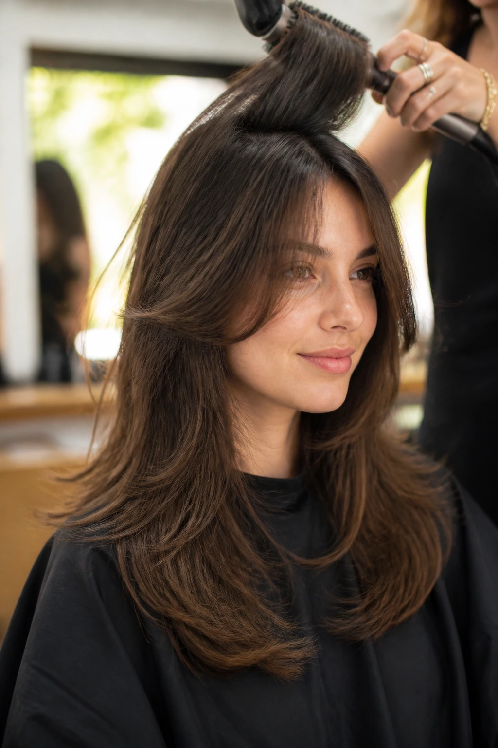 Real woman with butterfly layers being styled with a round brush at crown.
