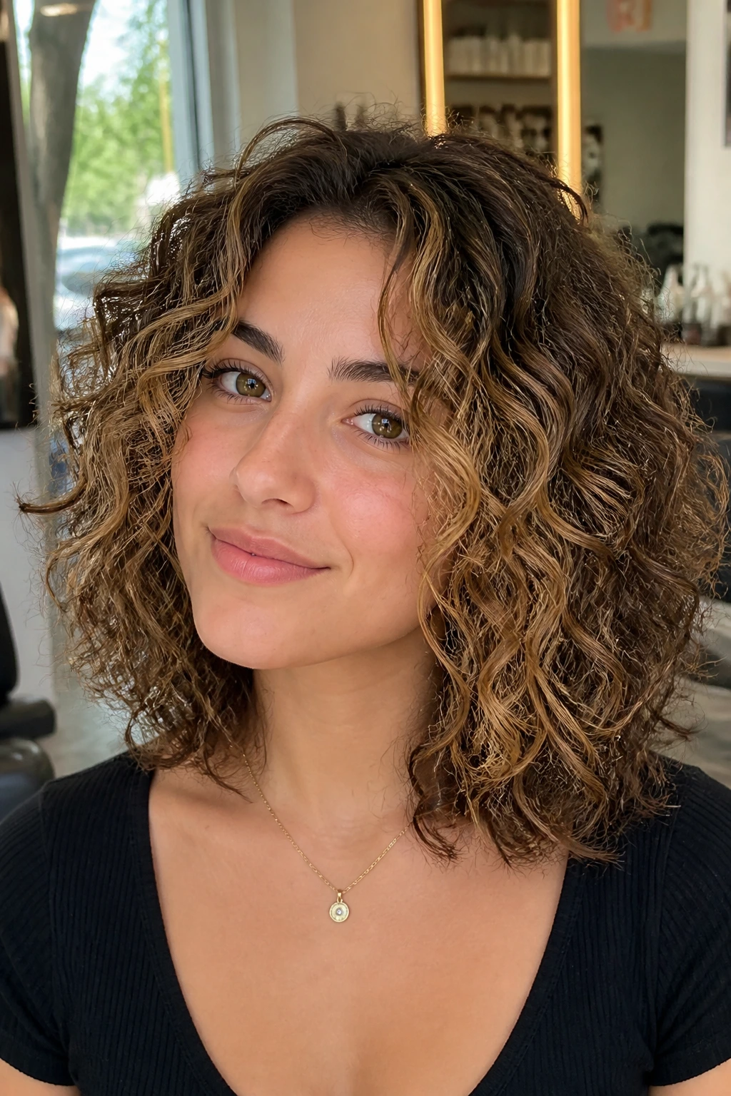 Portrait of layered curly lob with face-framing babylights around temples
