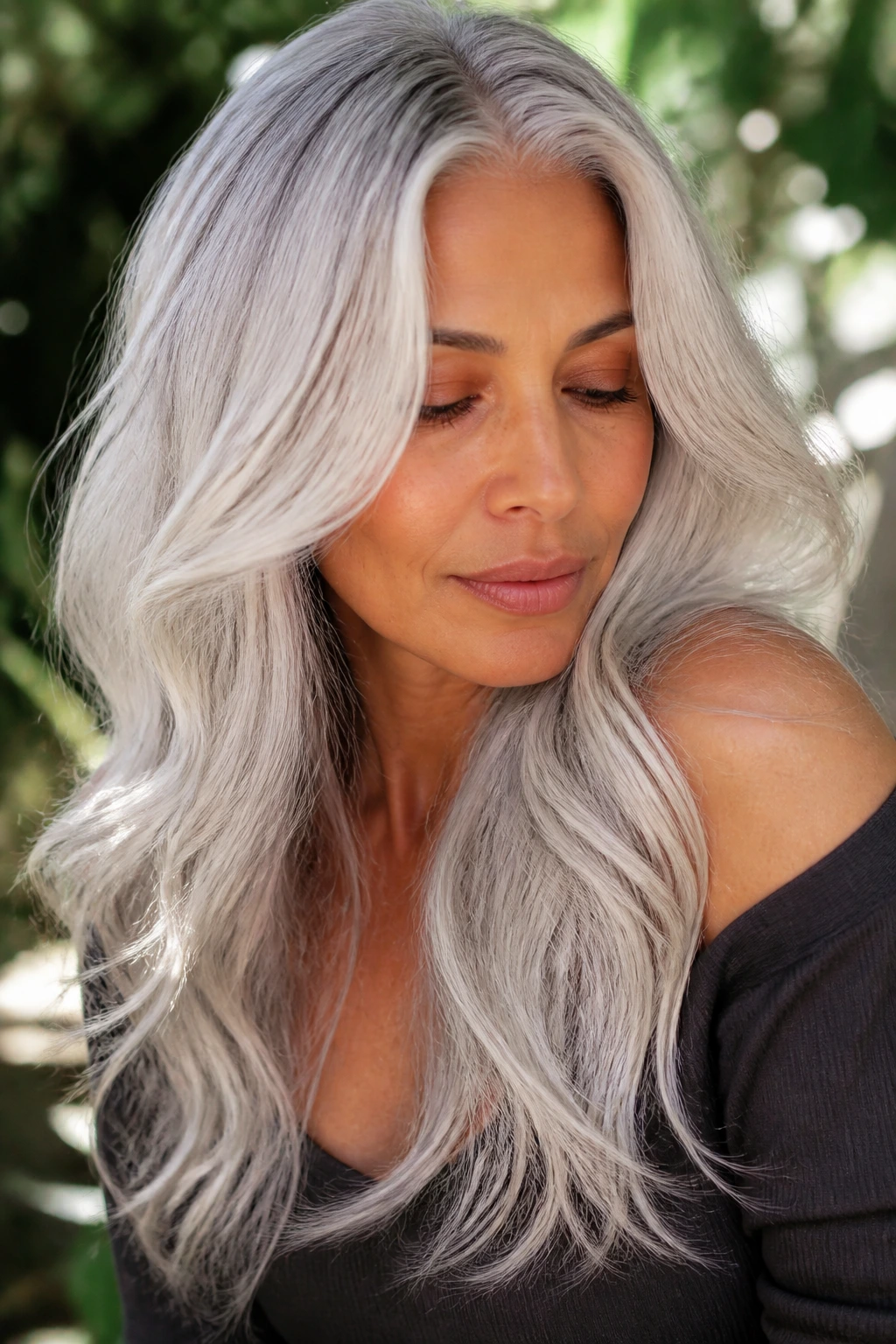 Portrait of a woman with long layered silver waves and root melt.