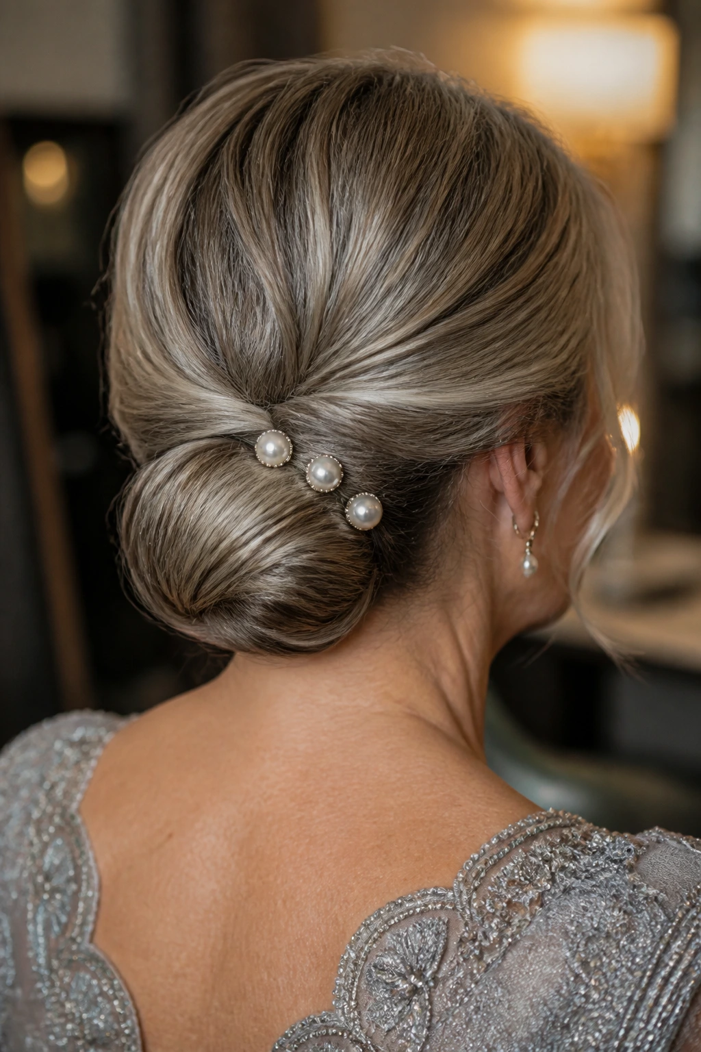 Close-up of a real woman with a tucked-in low bun and pearl pins.