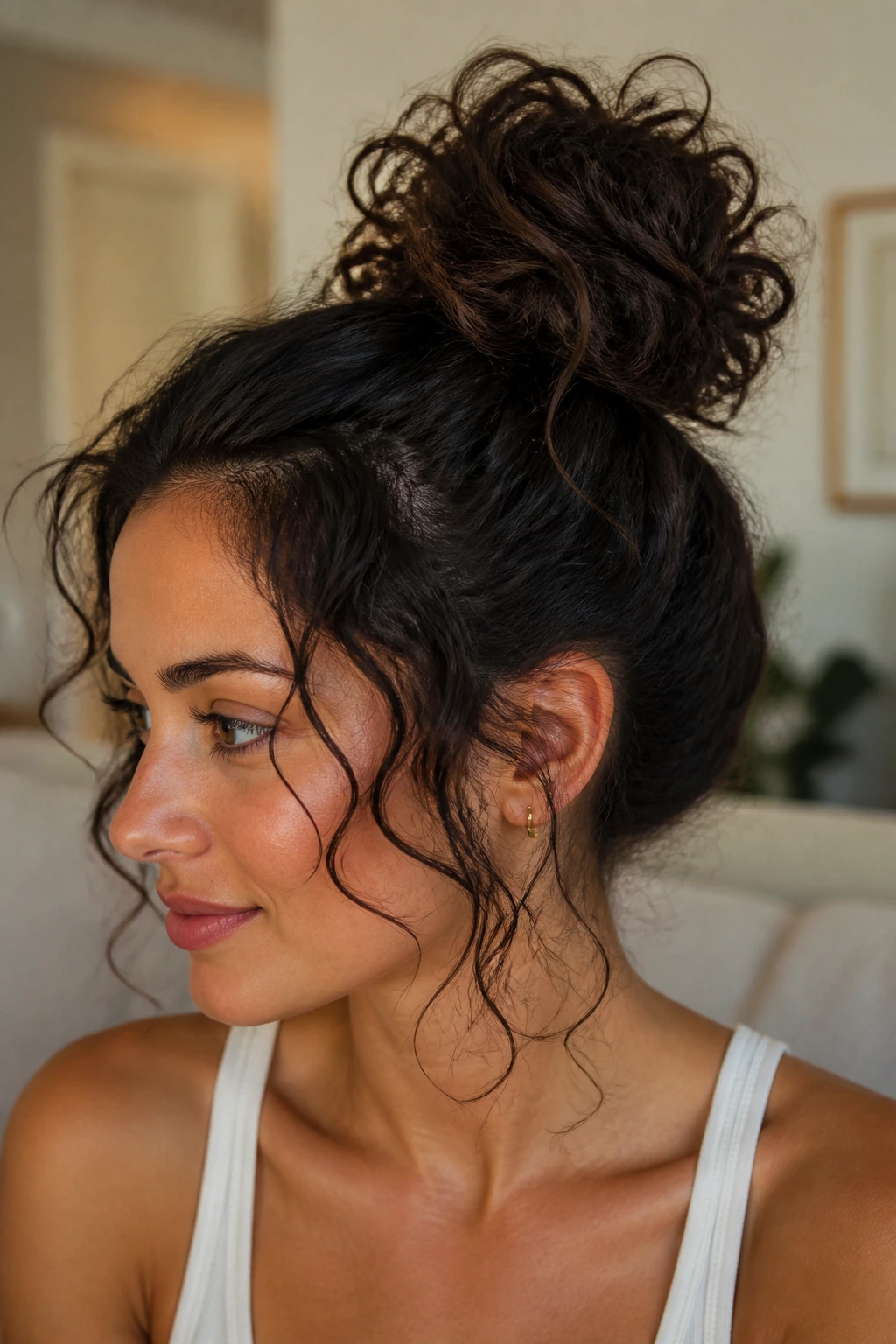 Close-up portrait of a real person with a messy curly bun and tendrils around the face