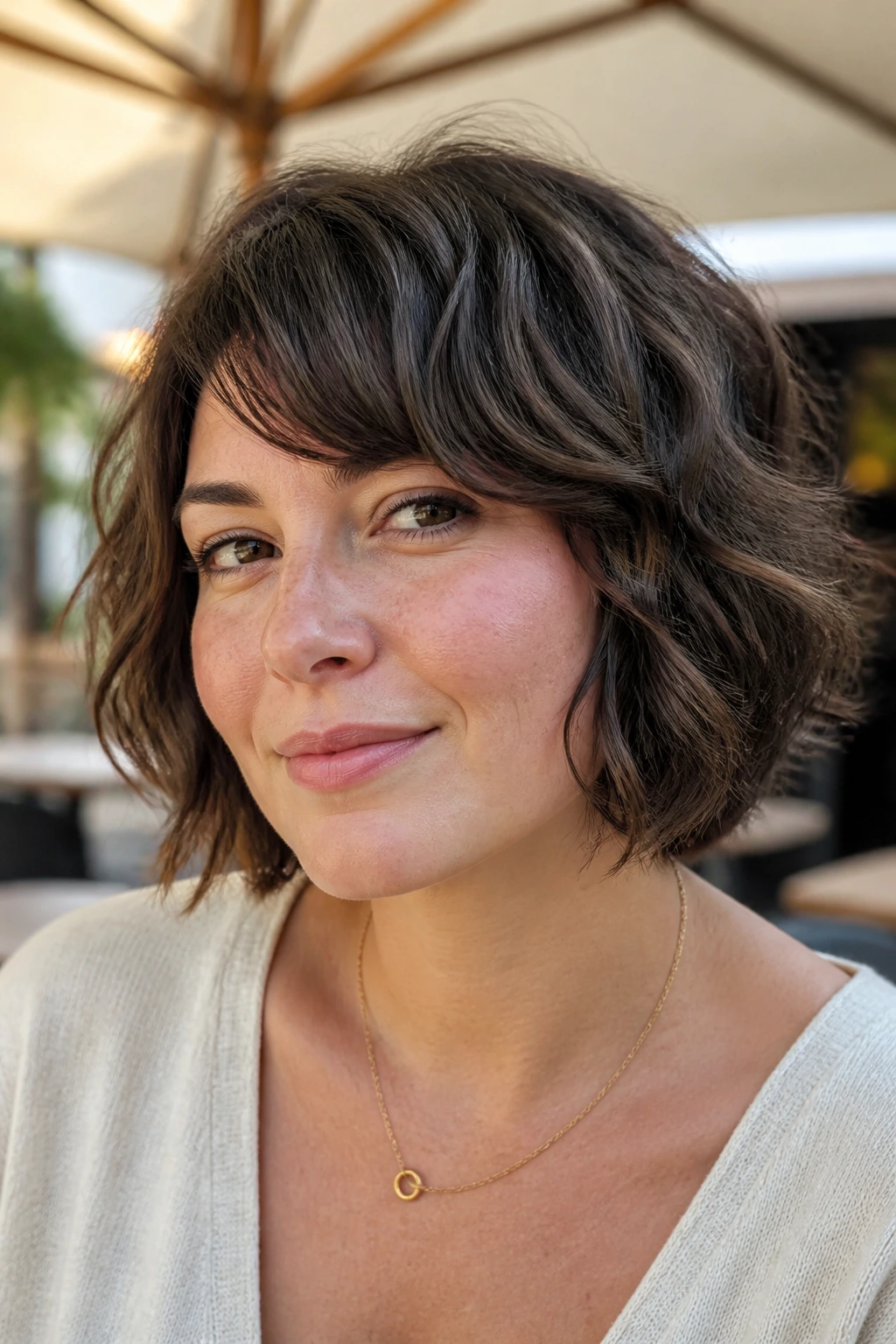 Close-up portrait of a real woman with micro-layered waves in a bob in outdoor sun
