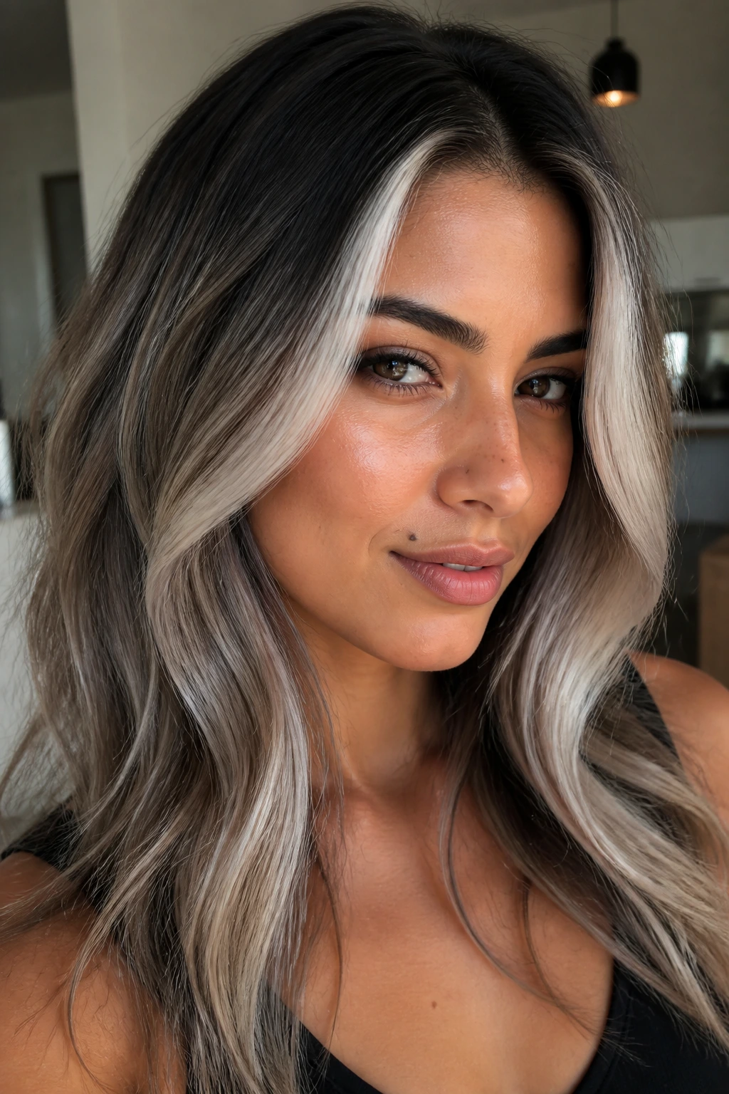 Portrait of a woman with platinum ash money piece and dark roots on olive skin