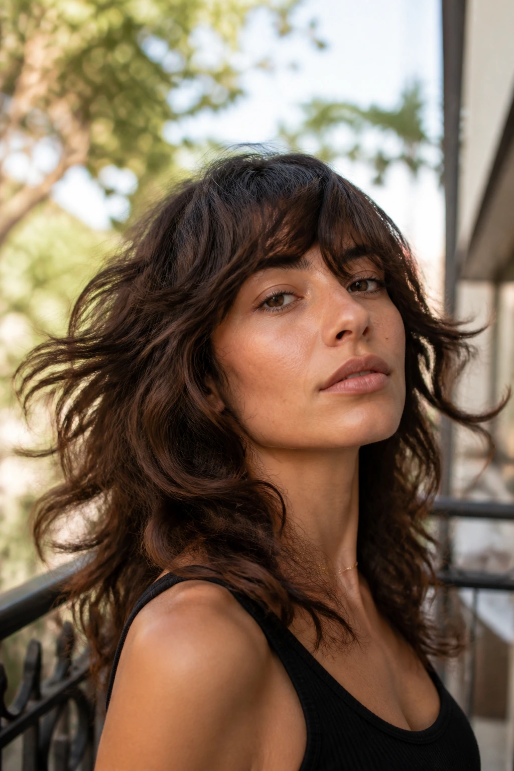Portrait of a real woman with movable wavy shag and side-swept bangs outdoors in daylight.