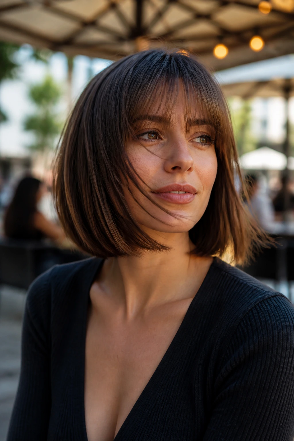 Real person with an A-line bob and bangs, hair shown with slight movement in daylight outdoor setting.