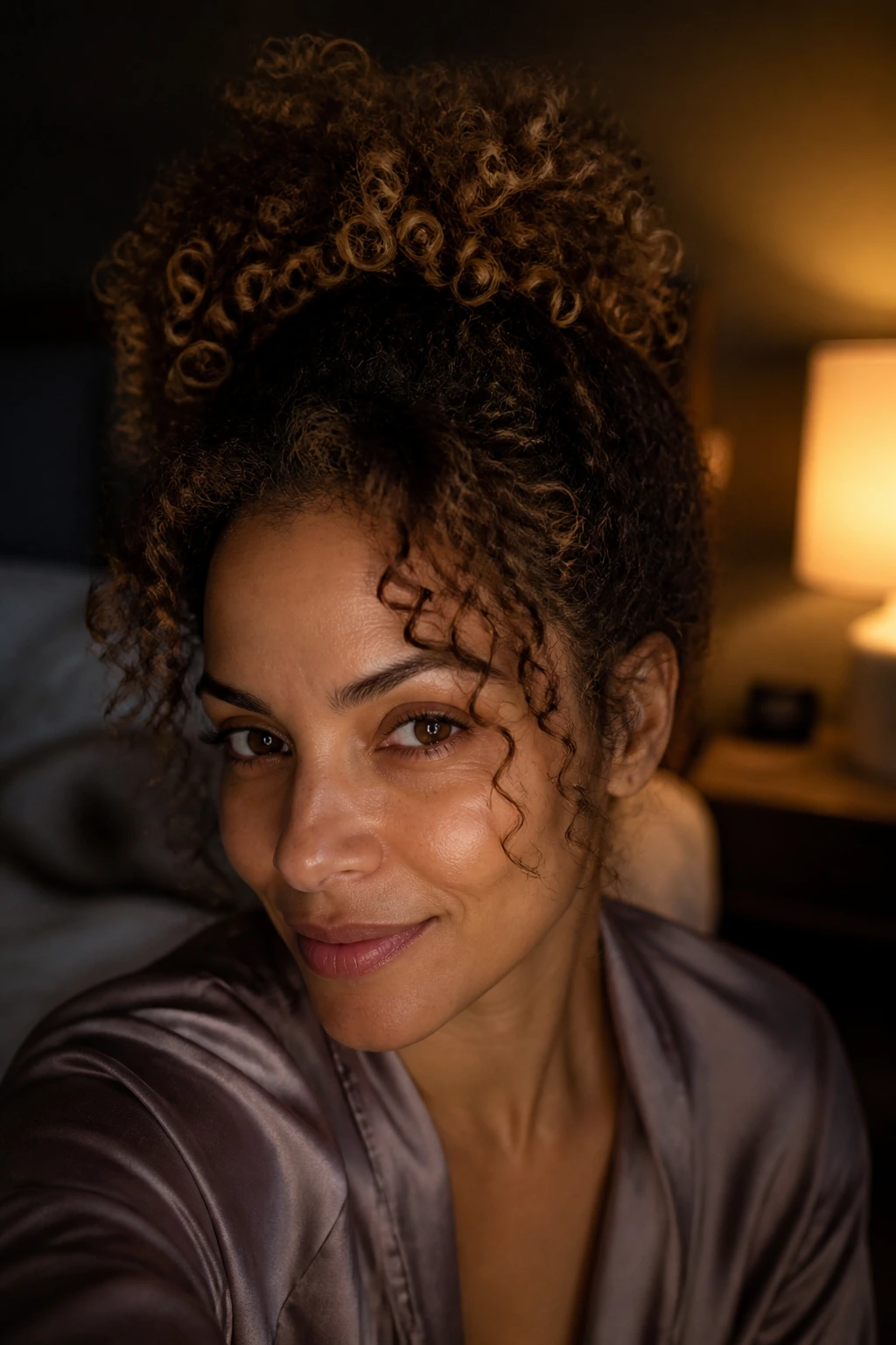 Portrait of a real woman with medium curly hair in a loose pineapple at the crown in a bedroom