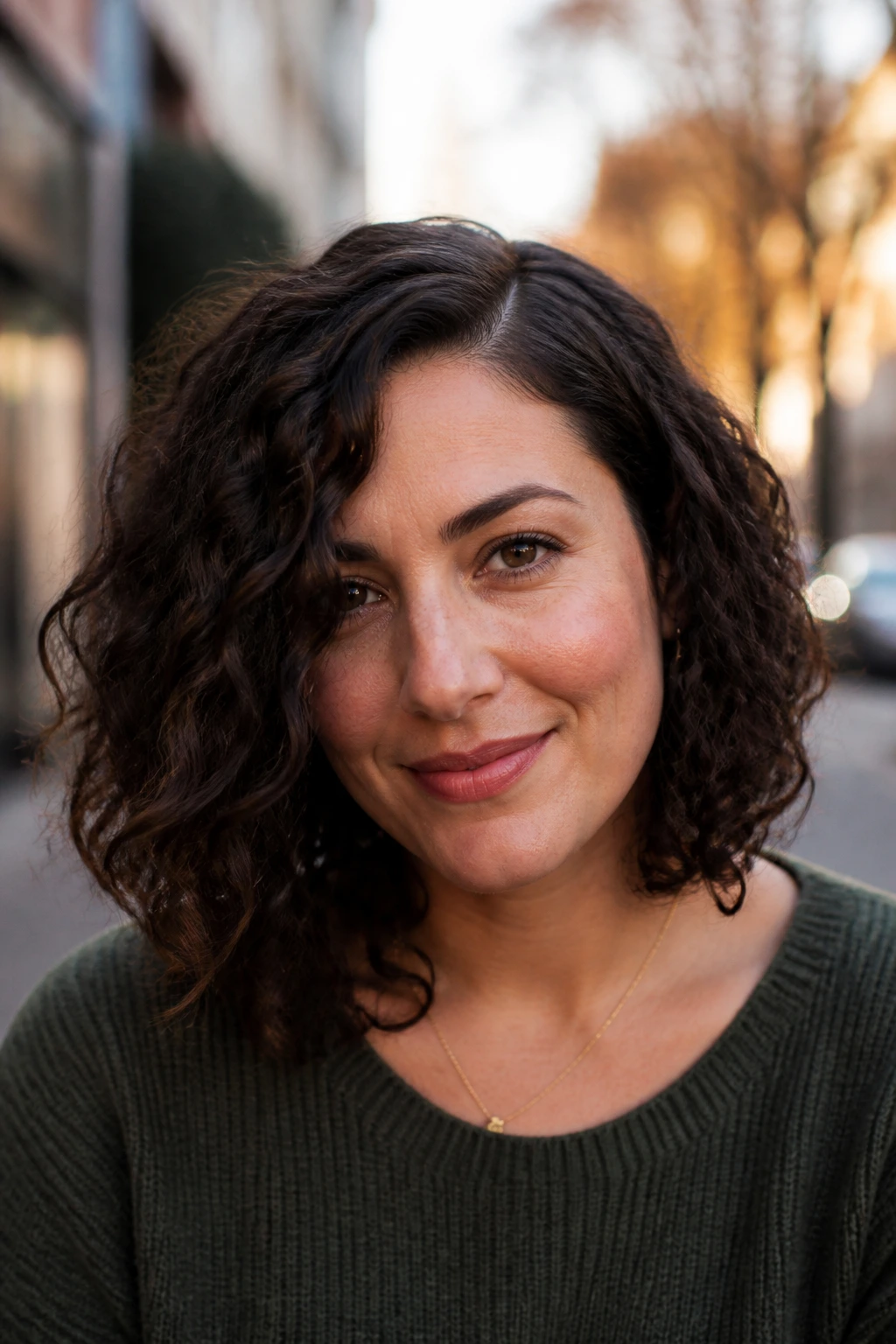 Close-up of off-center lob with low side part on a real woman with curls.
