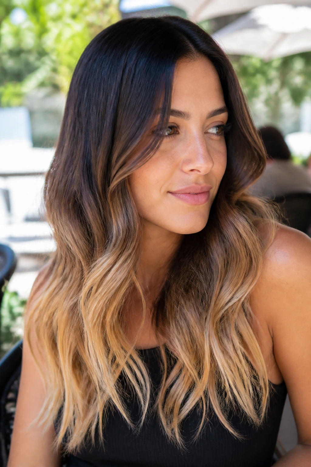 Close-up of a woman with subtle ombré blonde tips on dark hair outdoors