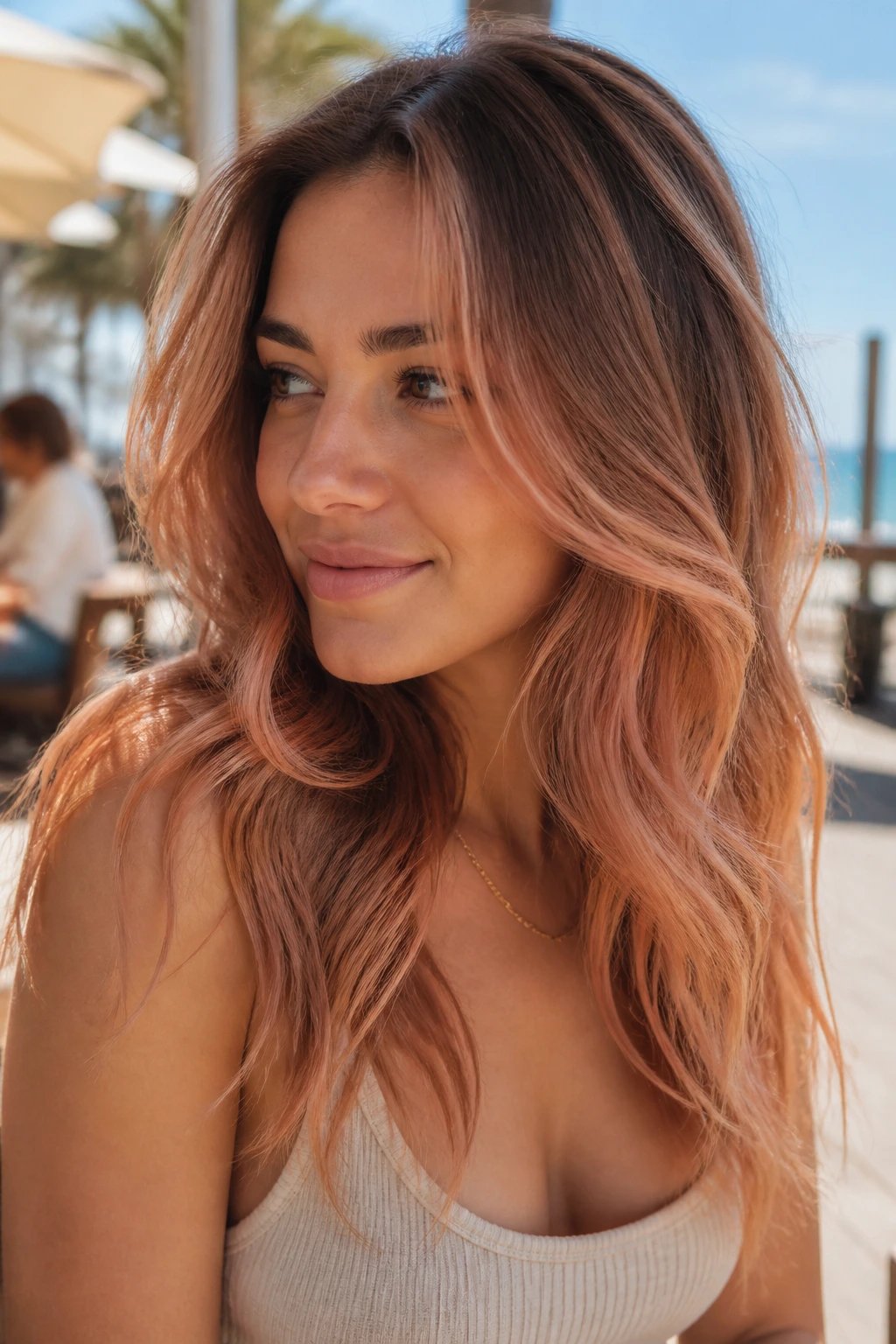 Close-up of a real woman with peach-tea balayage on tea-brown hair.