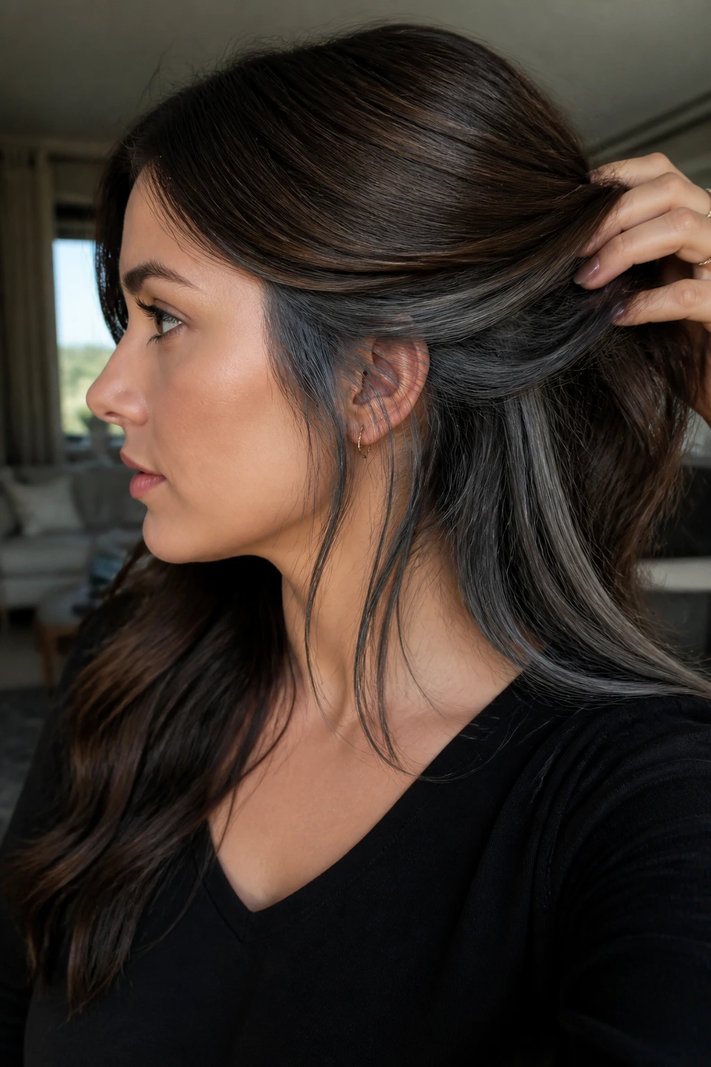 Portrait of brunette with charcoal peekaboo panels peeking from beneath hair.