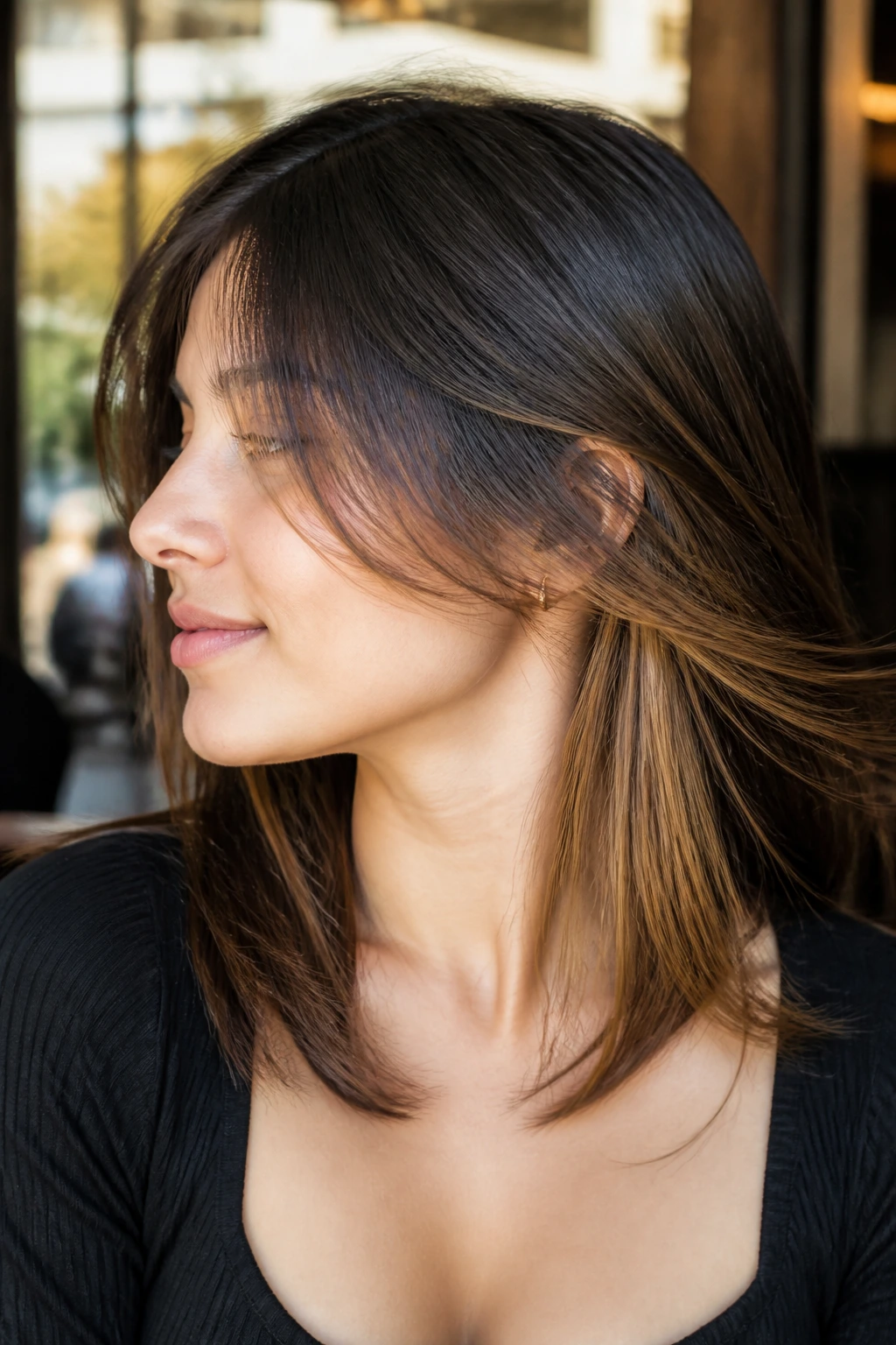 Close-up of a real person with caramel underlights peeking through the top layer of straight hair.