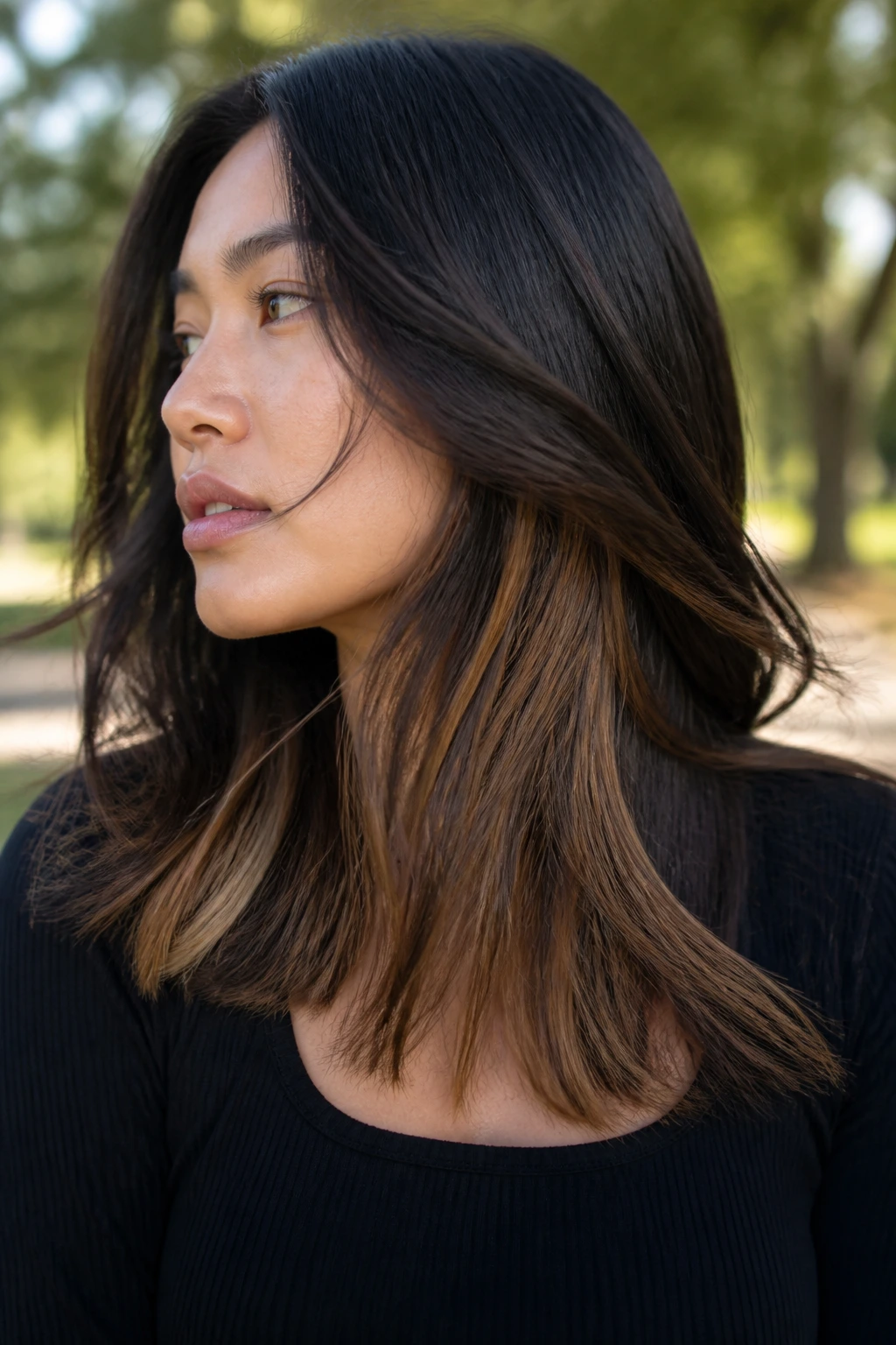 Close-up of peekaboo caramel underlights beneath dark hair layers