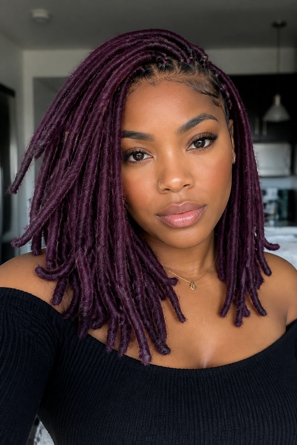 Plum faux locs on a real person in an apartment with soft light.