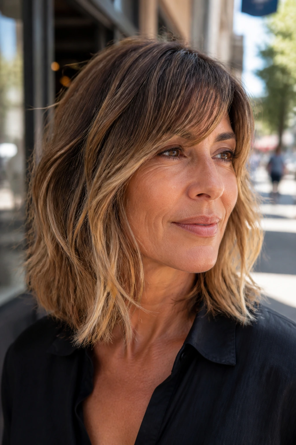 Woman with razored long bob and light ends in sunlight.