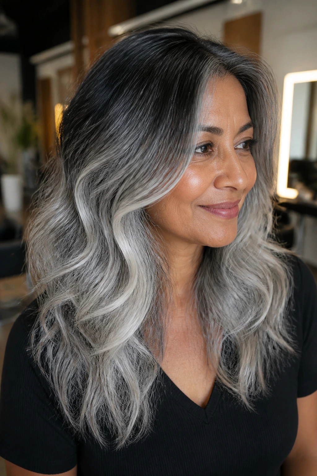 Portrait of a woman with a root-melt grey hairstyle showing dark roots fading to silver