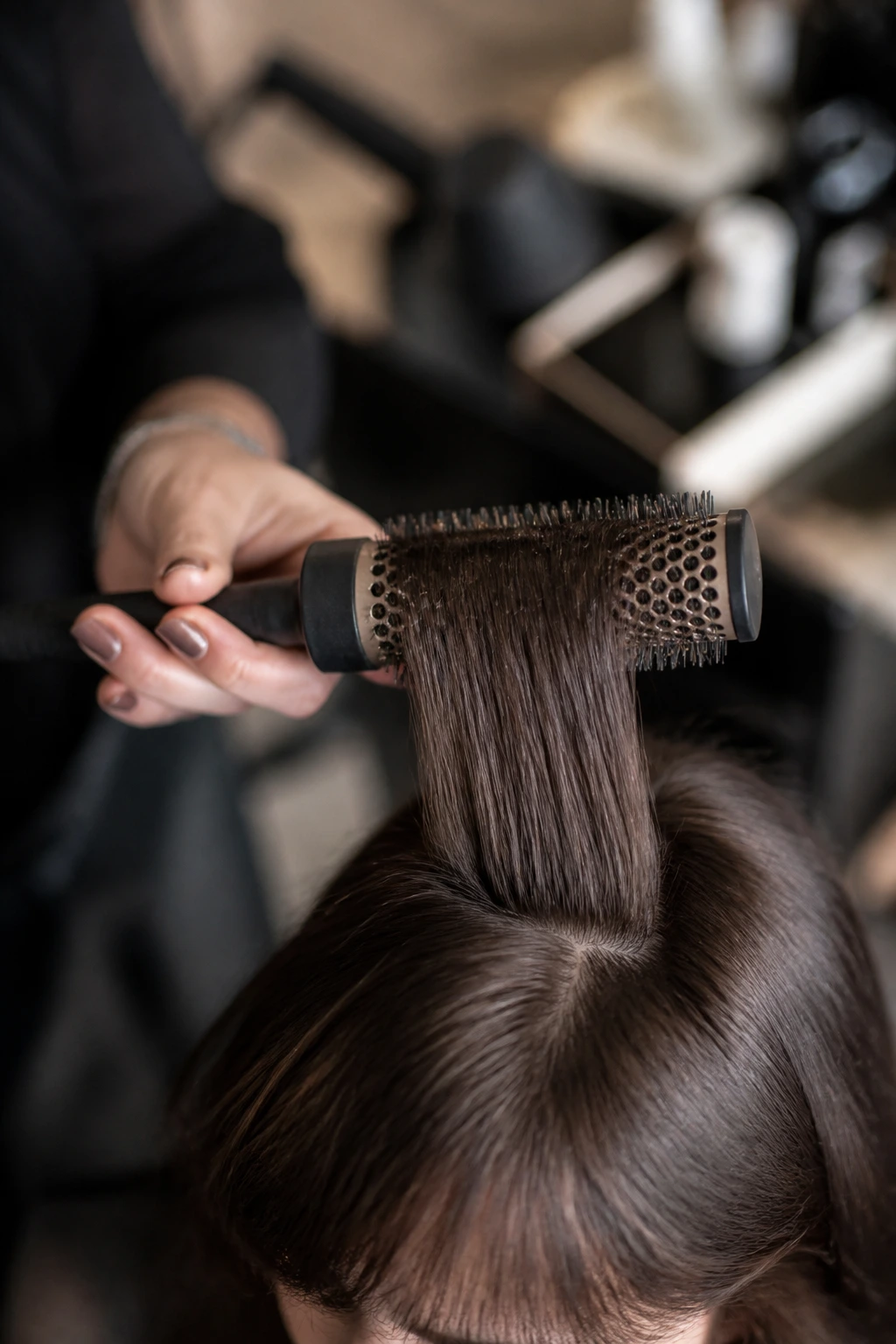 Round brush and fringe held in hand in salon setting