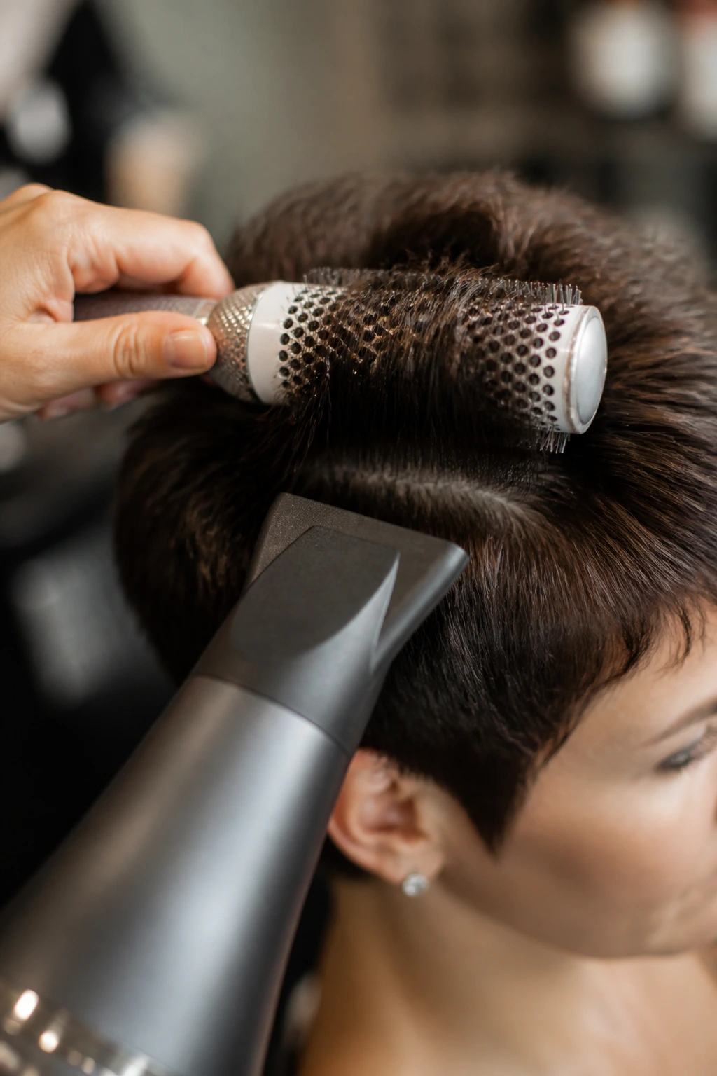 Close-up of a round brush shaping thick hair in a salon