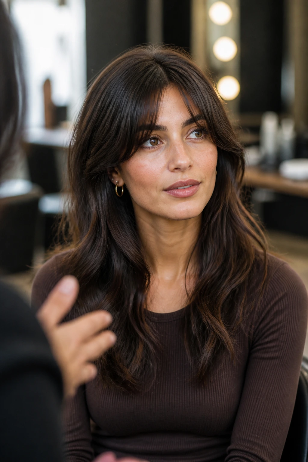 Portrait of a person in a salon chair discussing bangs with a stylist