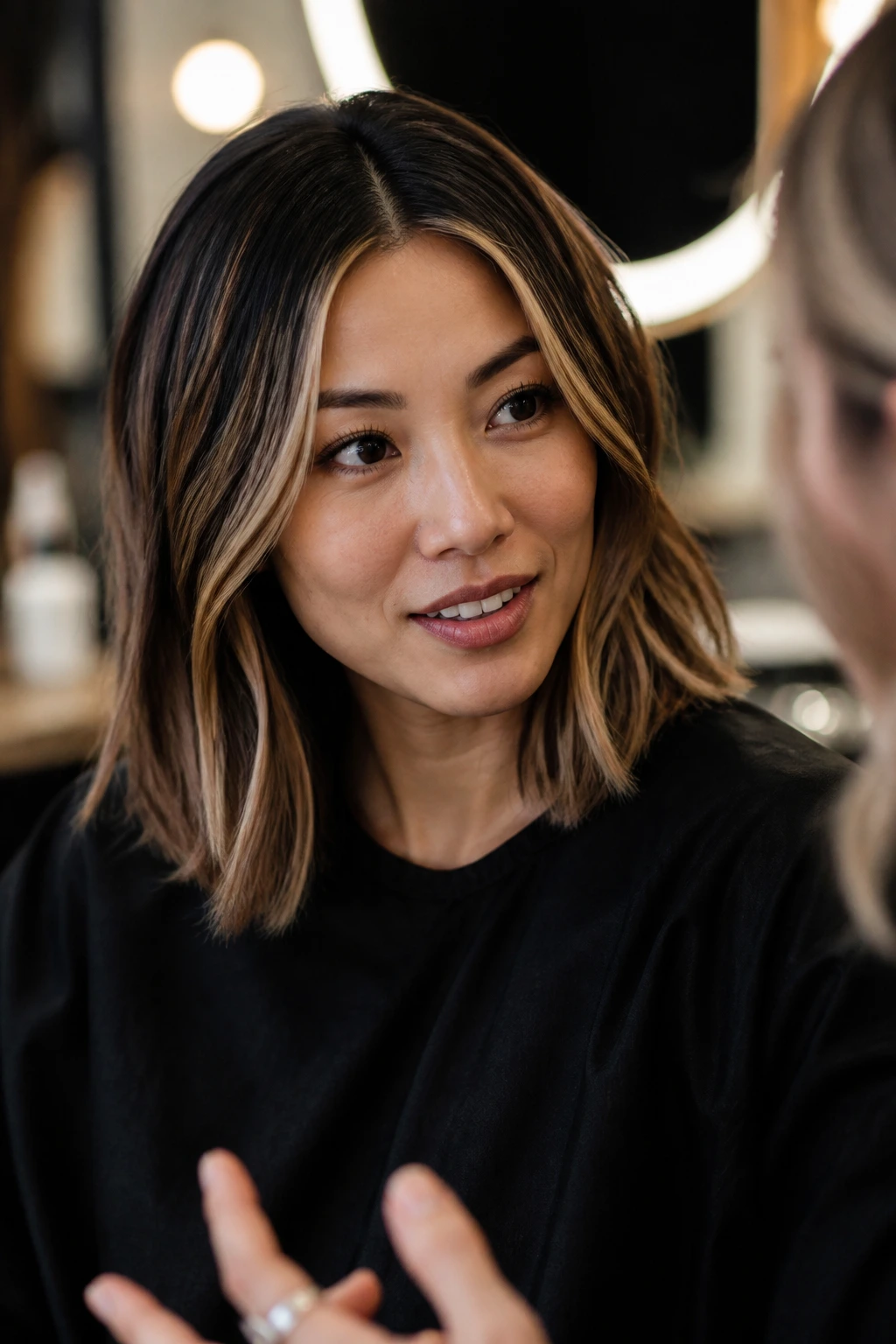 Portrait of a real client in a salon chair discussing hairstyle with a stylist.