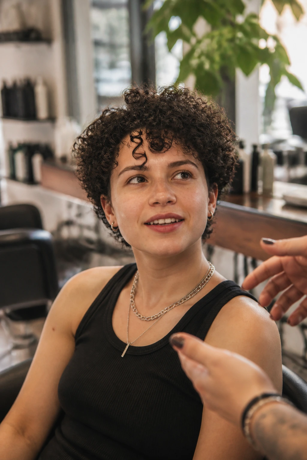 Portrait of person in salon chair discussing curly haircut with stylist