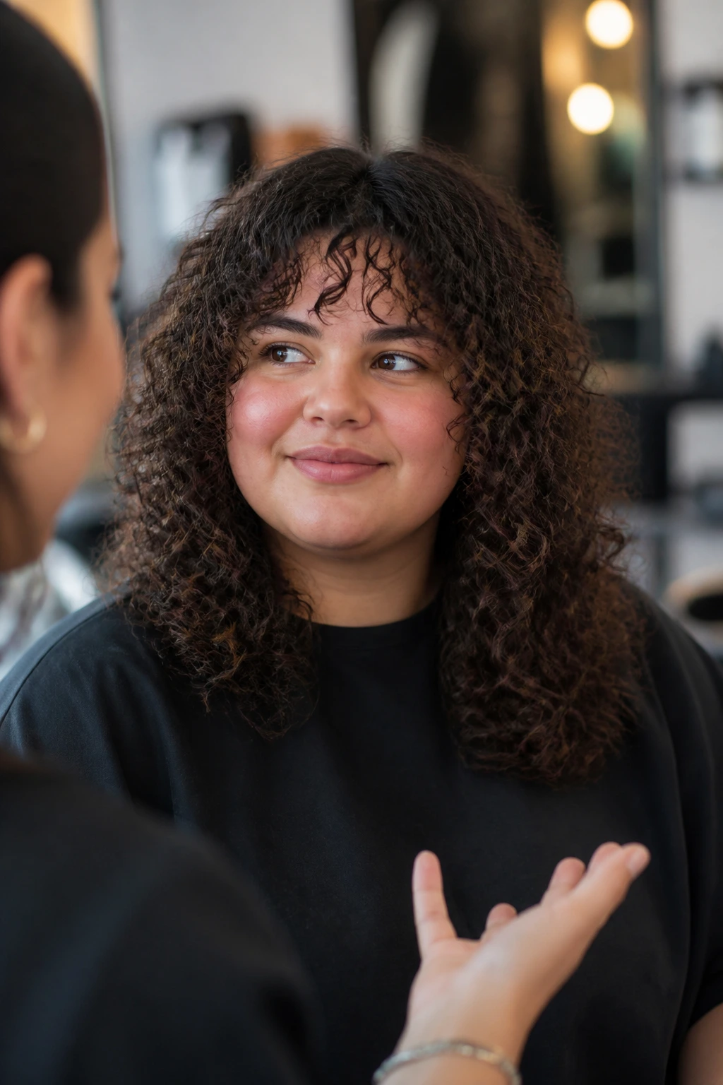Client in a salon with curly textured layers, ready for advice