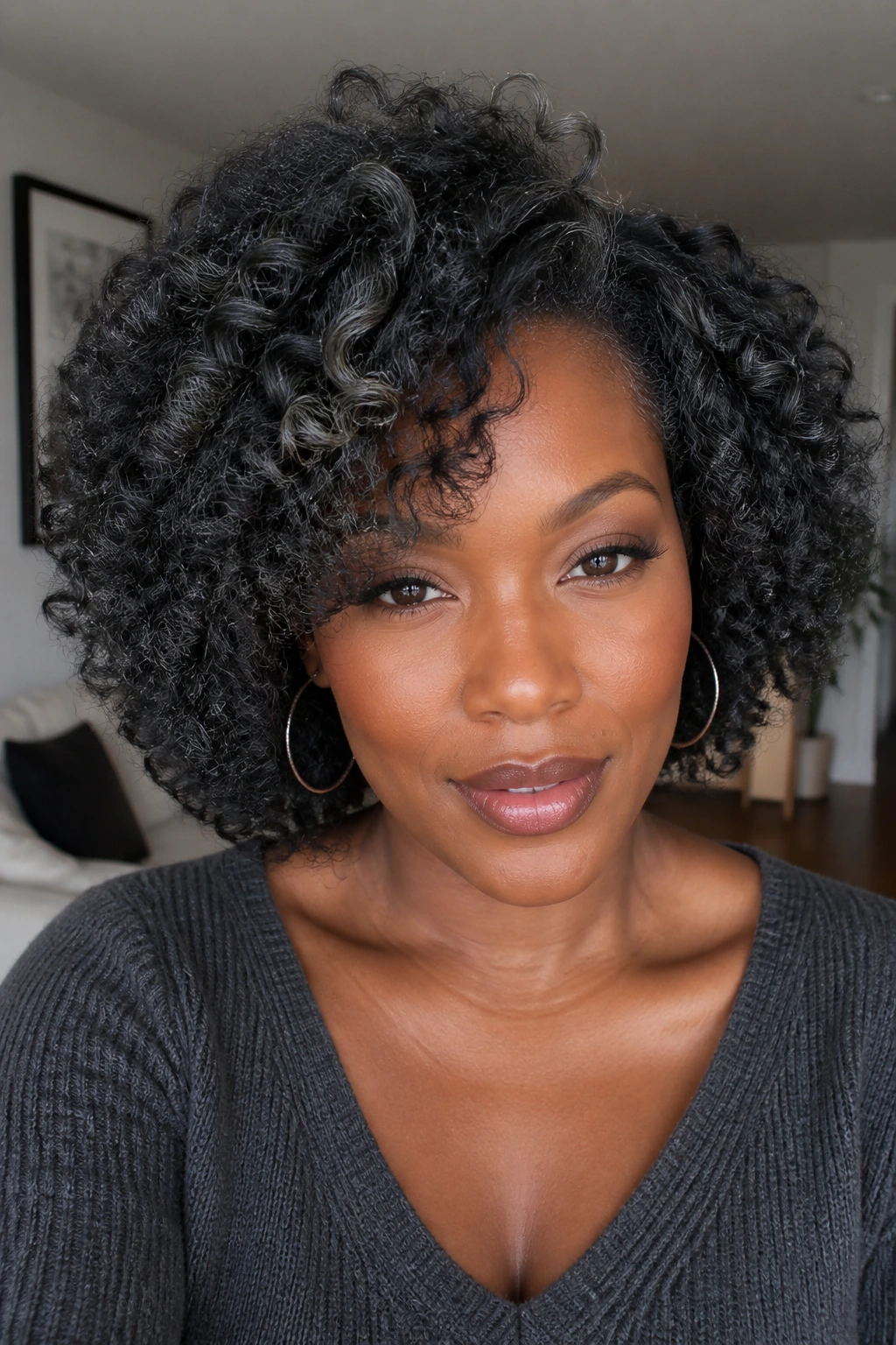 Close-up of a real person with charcoal curls and silver flecks on deep skin.
