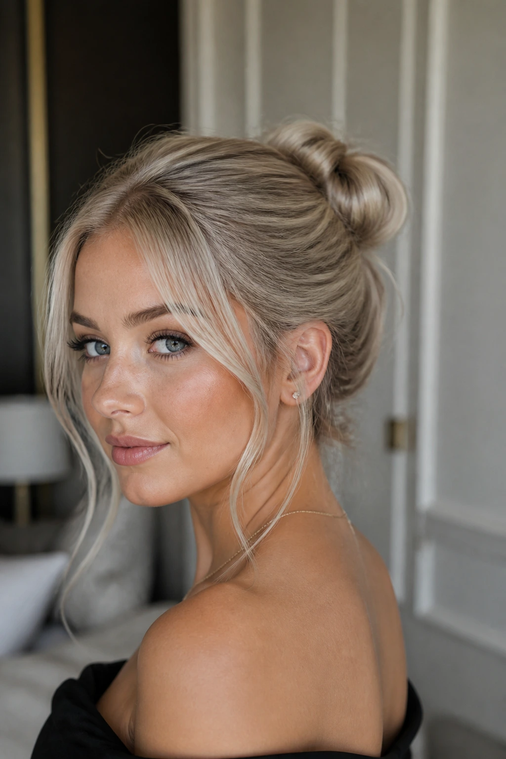 Close-up of a real woman with a satin bun and piecey tendrils in ash blonde