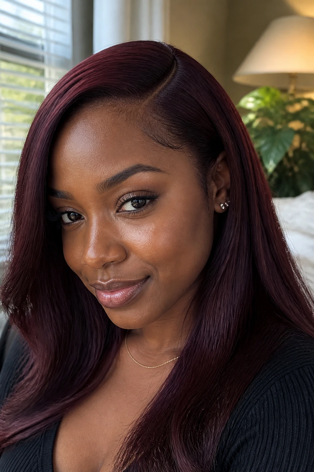 Close-up of a real person with a cherry cola side-part sew-in on deep skin tone.
