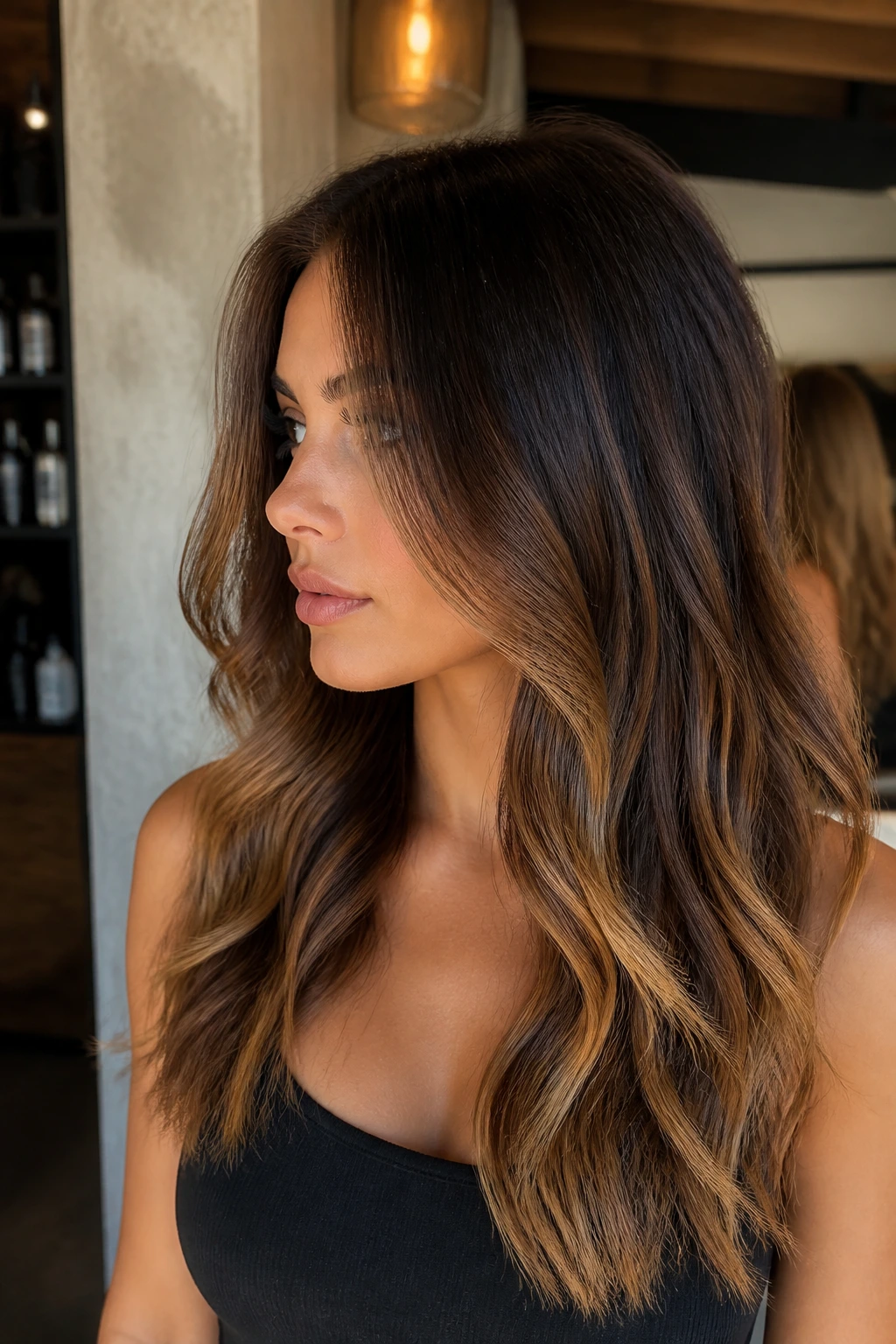 Brunette with shadow-root balayage and caramel ends in profile