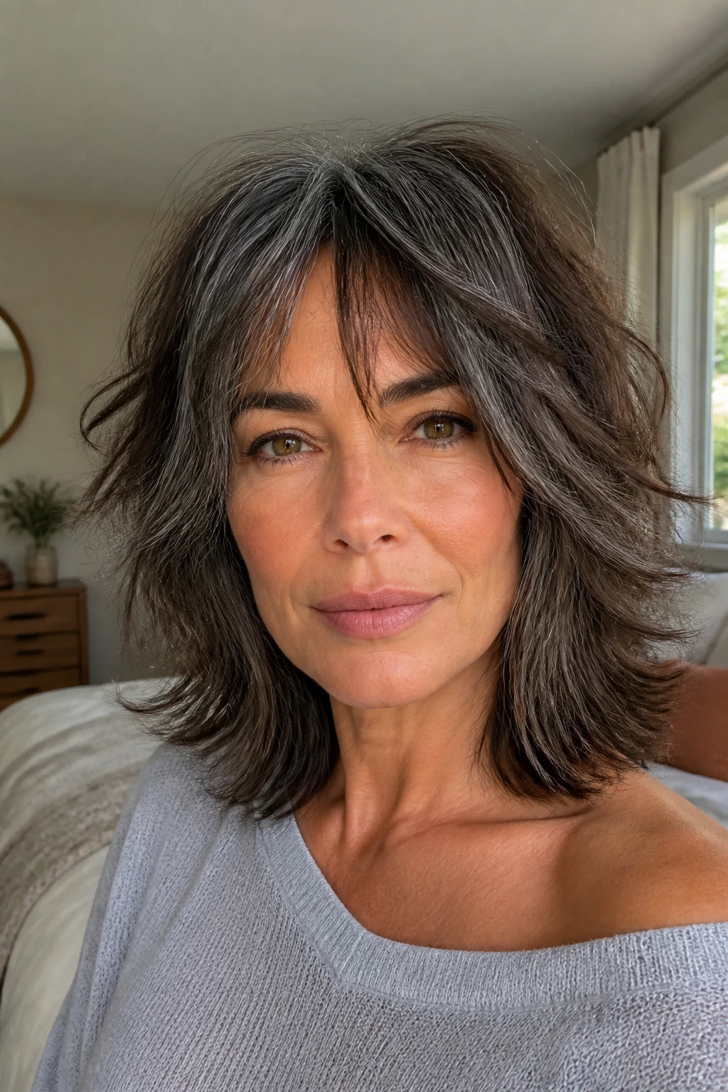 Close-up portrait of a real woman with a choppy shag and airy ends showing grey highlights on dark brunette hair