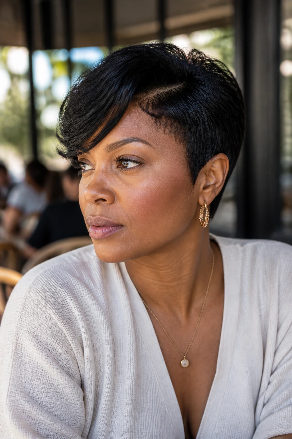 Real woman with a side-swept two-block pixie, long top swept to one side.