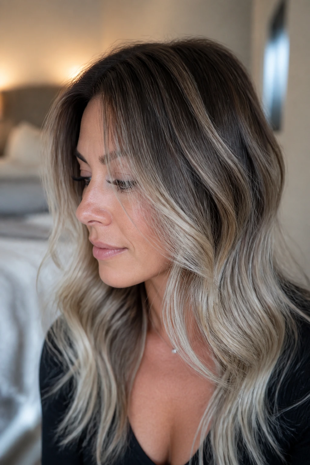 Close-up portrait of brunette with silver-blonde hair featuring natural root growth and icy ends in soft window light