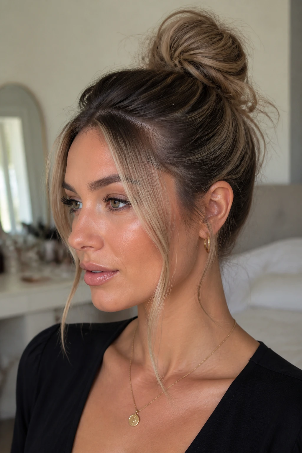 Close-up of a real woman with a sleek-root bun and money-piece face framing