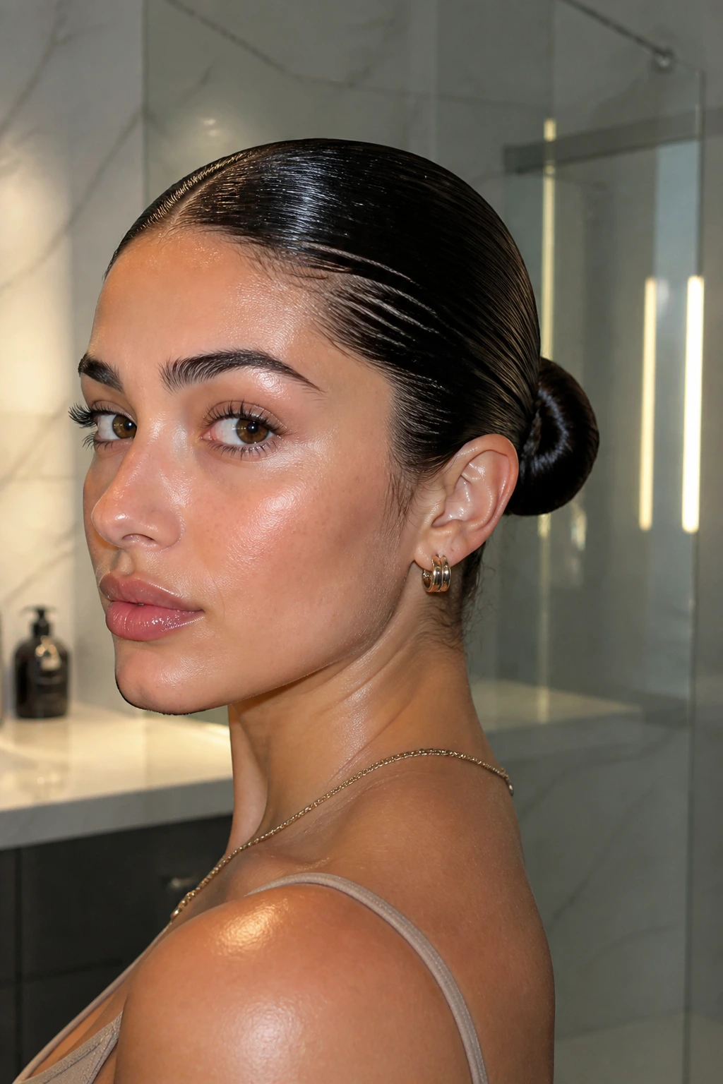 Portrait of a woman with a wet slick-back low bun in a modern bathroom