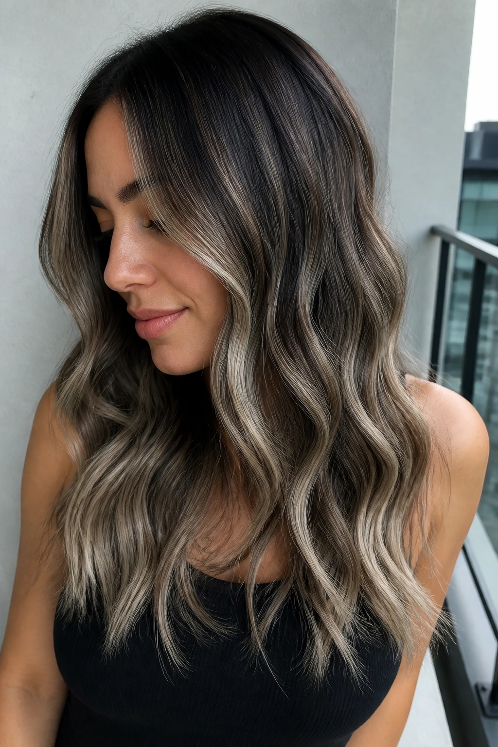 Close-up of a real woman with smoke-and-ash balayage on dark waves.