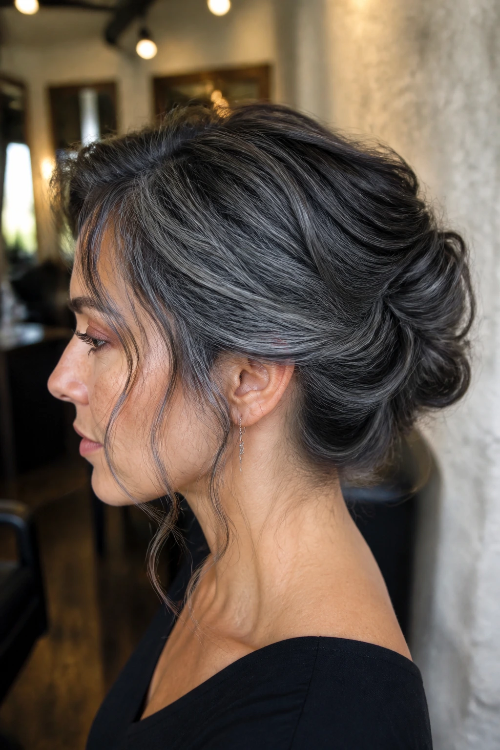 Profile of a real woman with a textured smoke-gray updo, visible nape and hairline