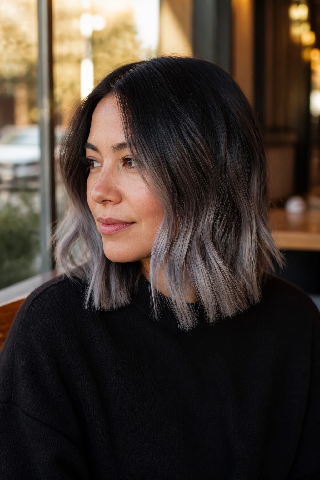 Real person with a brown-to-grey smoky balayage lob showing a gradient from dark root to grey ends