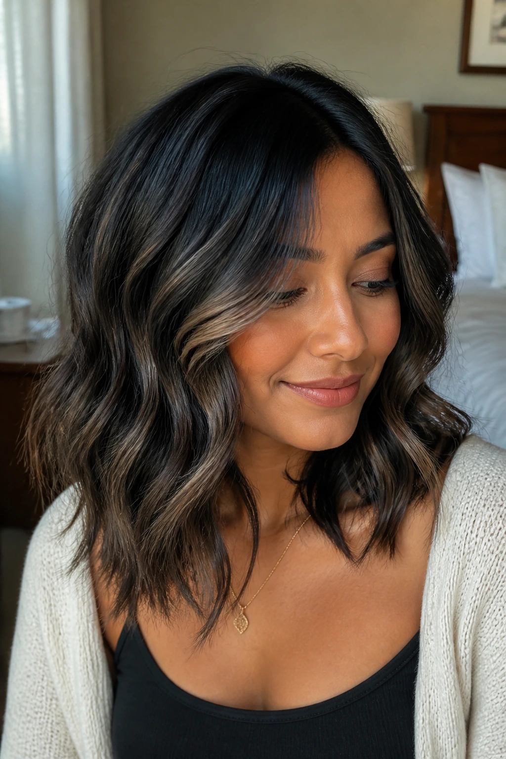 Close-up of a real woman's hair with smoky balayage ribbons in beachy waves on medium skin