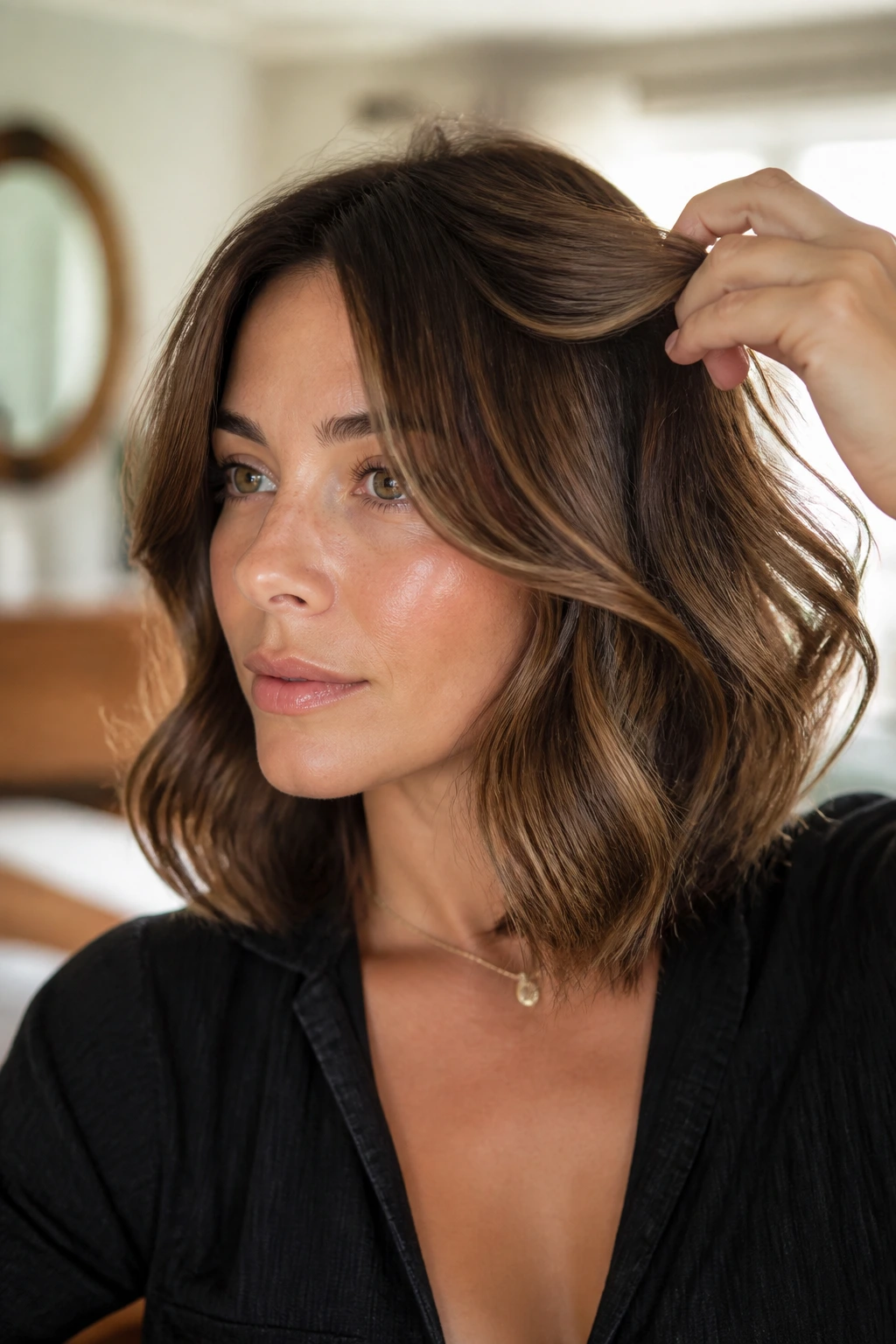 Real woman styling soft curls with her hands in a warm setting