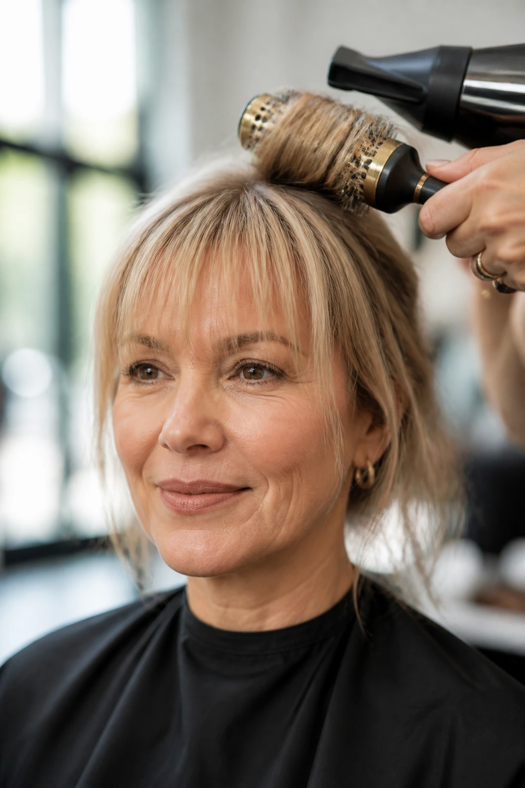 Woman with soft fringe being styled with a round brush and blow-dryer